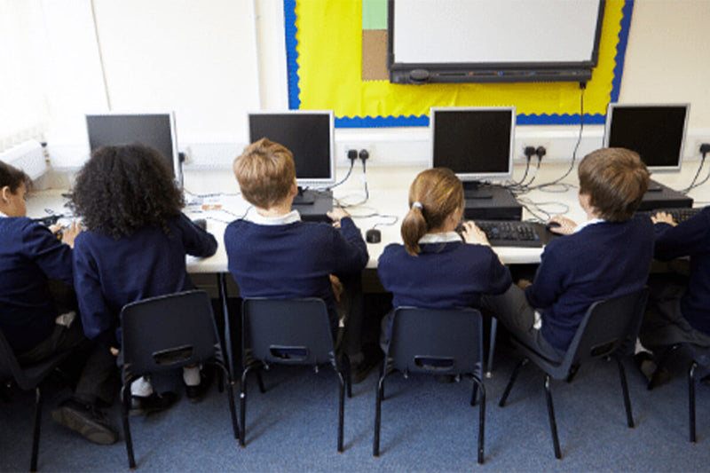 School children facing computers in classroom