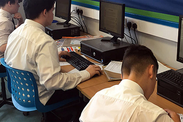 Pupils sit at desktop computers working in the ICT suite